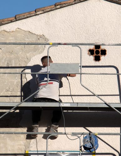 travailleurs du bâtiment faisant un ravalement de la façade d'une maison